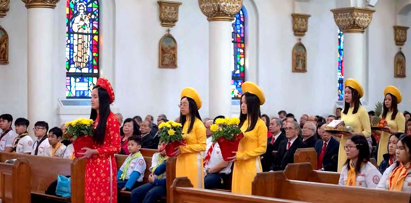 Young women in traditional clothing process to the altar with gifts.